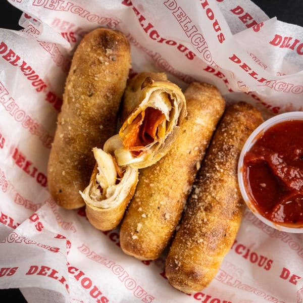 Five Star Pizza pepperoni and cheese rolls, one cut open, with a side of marinara sauce.