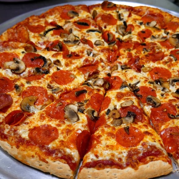 A whole Five Star Pizza with pepperoni and mushrooms, sliced and ready to eat.