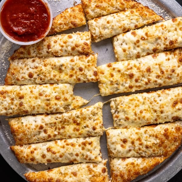 Five Star Pizza's cheesy breadsticks, golden brown with melted cheese, served with a side of marinara sauce.