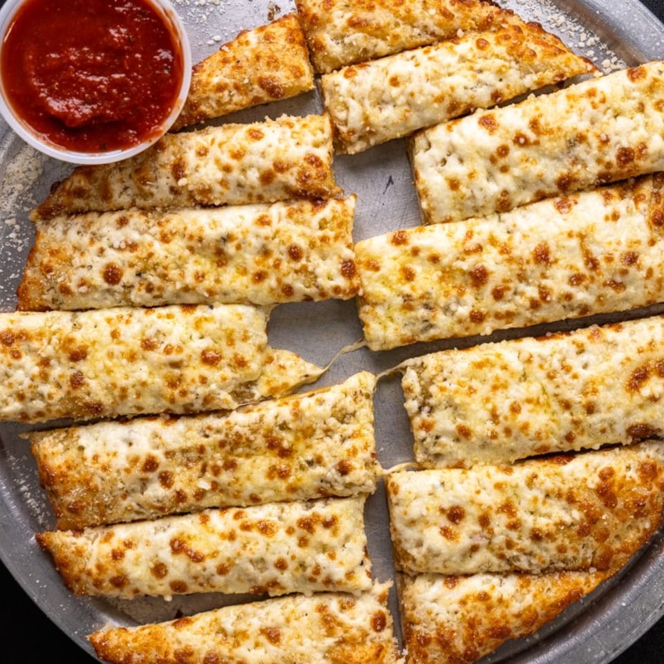 Five Star Pizza's cheesy breadsticks, golden brown with melted cheese, served with a side of marinara sauce.